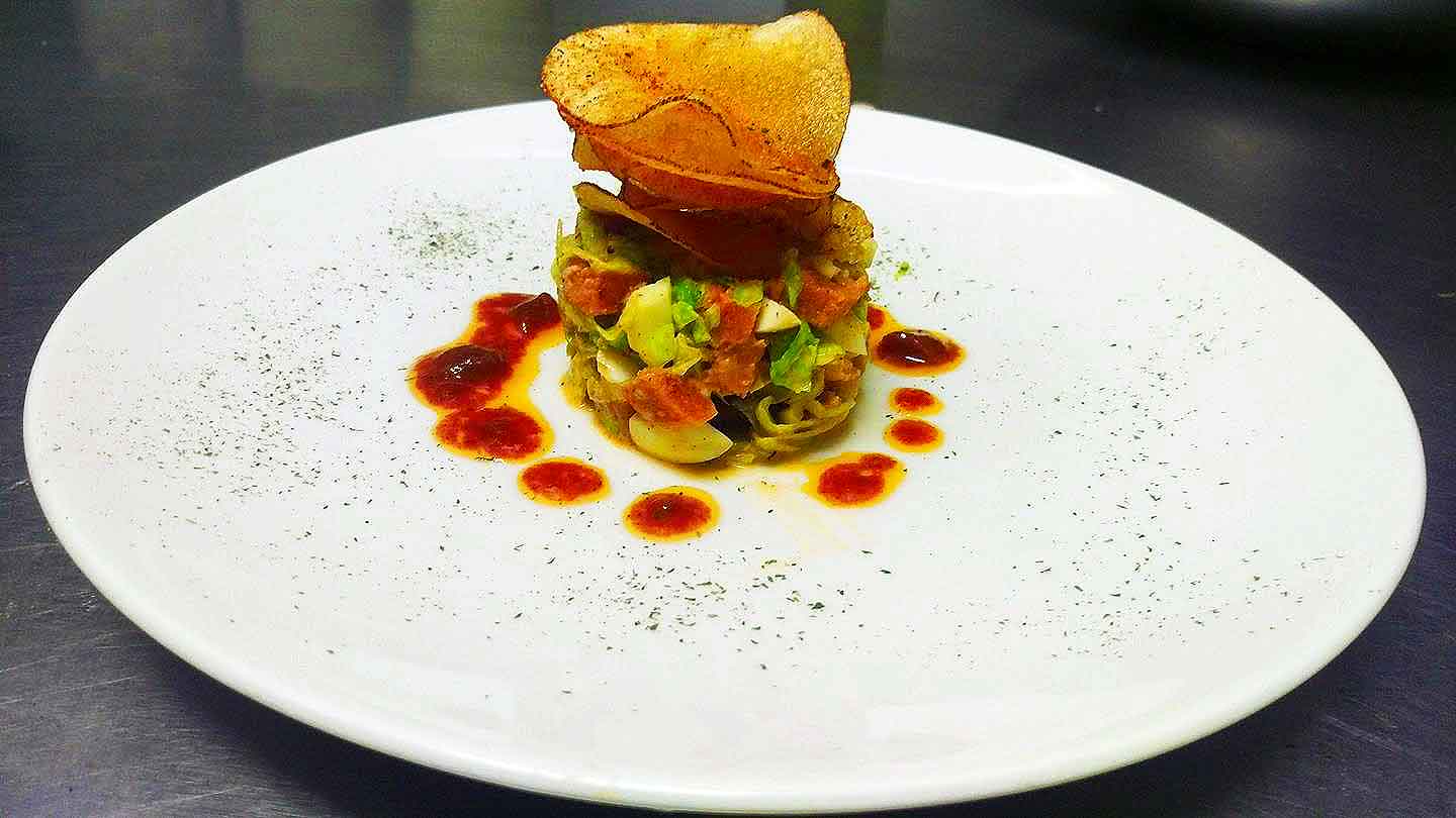 Ahi stack with seafood and avocado garnished with crunchy chips on top.
