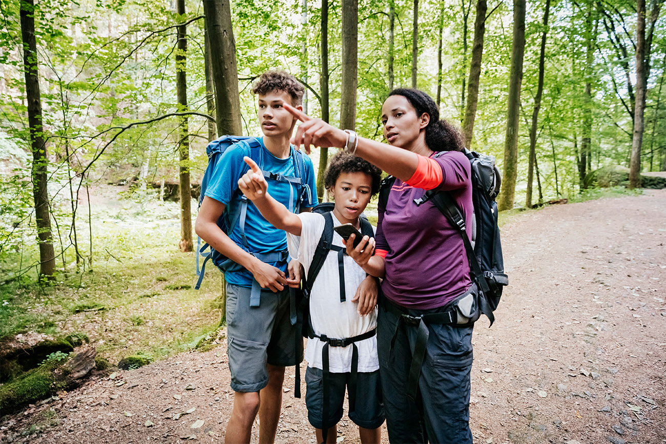A mother pointing to something on the trail while out hiking with her two sons out the afternoon.
