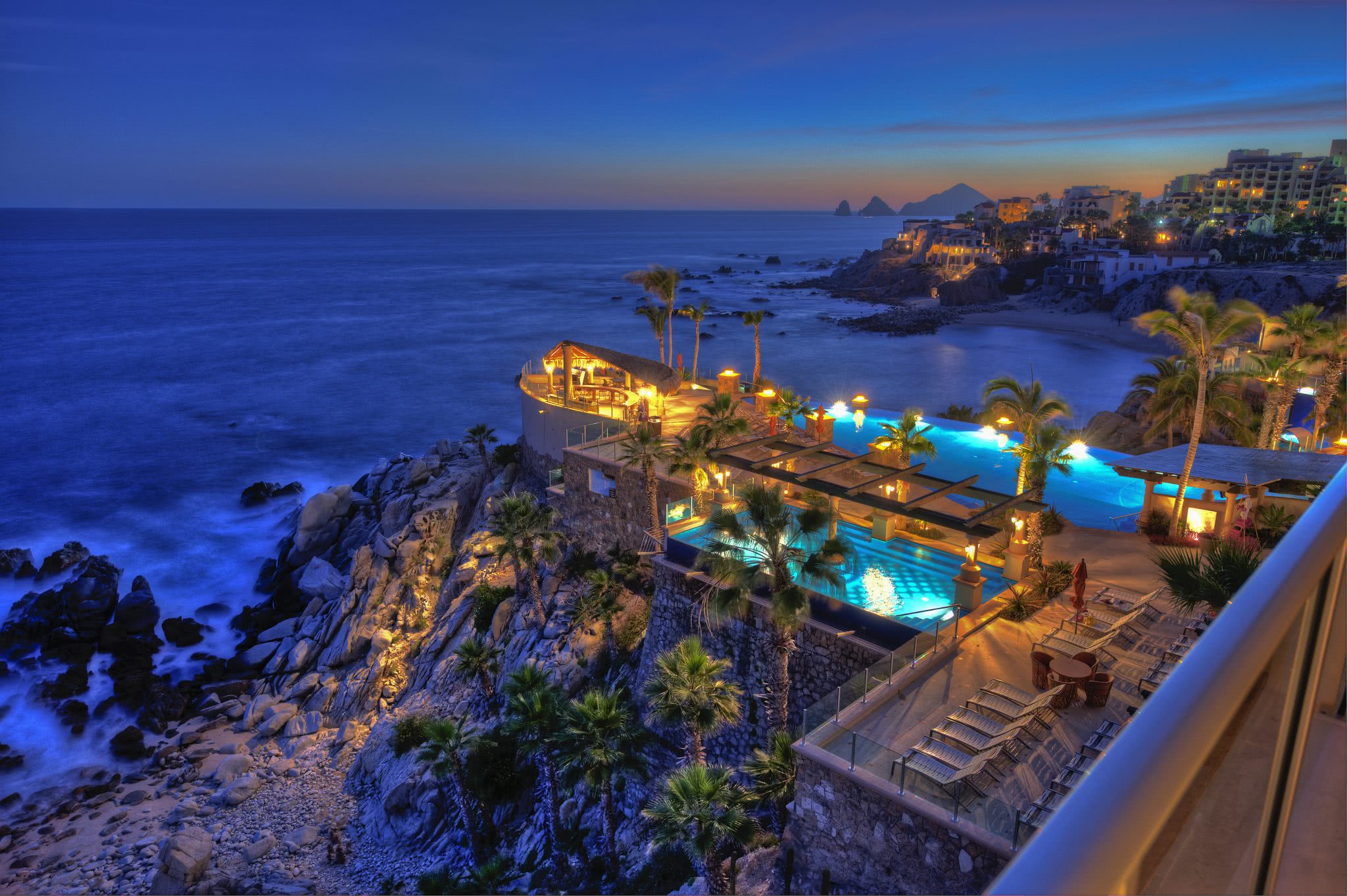 Sirena del Mar resort in Cabo San Lucas at dusk looking out over the pools, cliffs, and ocean.