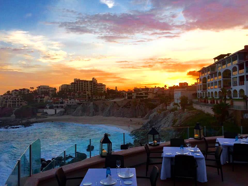 Sunset over the hills with tables on the deck at Estrella Restaurant at Sirena del Mar resort in Cabo San Lucas