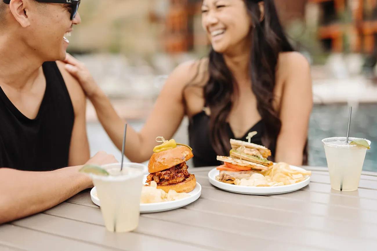 Two women eating sandwiches near a Hyatt Vacation Club resort pool