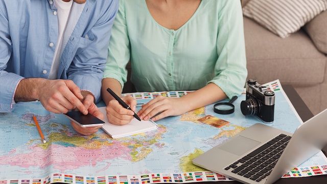 Couple planning vacation trip, searching information and writing notes