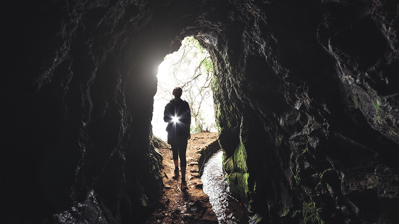 Woman with flashlight exploring a cave