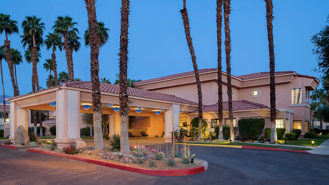 Tall palm trees surround the entrance to the resort