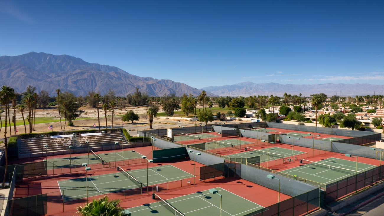 Aerial view of tennis courts on a sunny day with mountains in the background