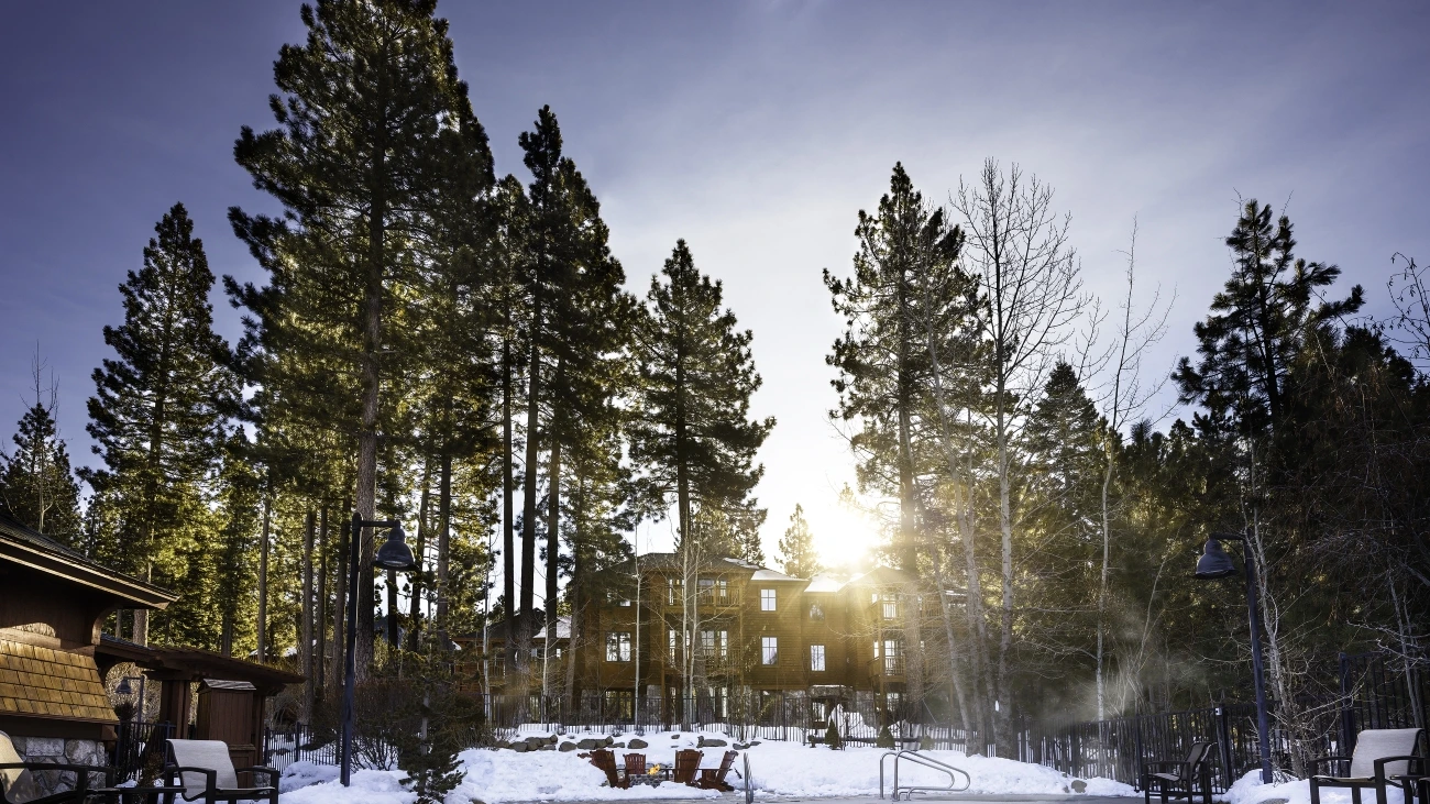 A snowy landscape, evergreens, and a resort with steam rising from a whirlpool spa