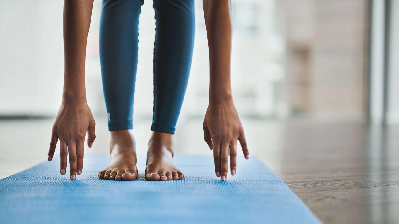 Floor view of yoga mat, bare feet, and hands in a yoga pose 