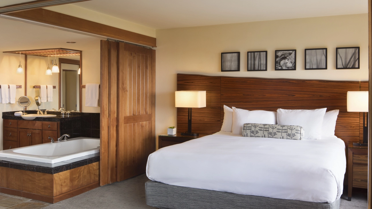 Bedroom with sliding privacy doors in front of a whirlpool tub, vanity, and mirror