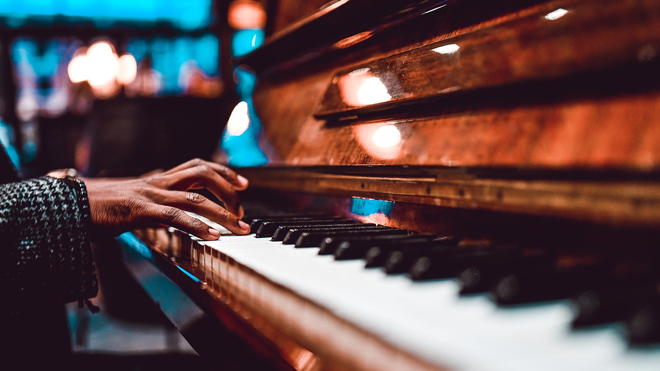 A person playing a piano with ambient light in the background