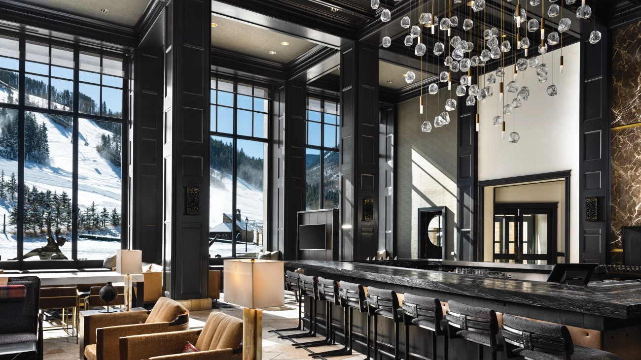 A spacious and modern lobby is filled with chairs and a black marble bar