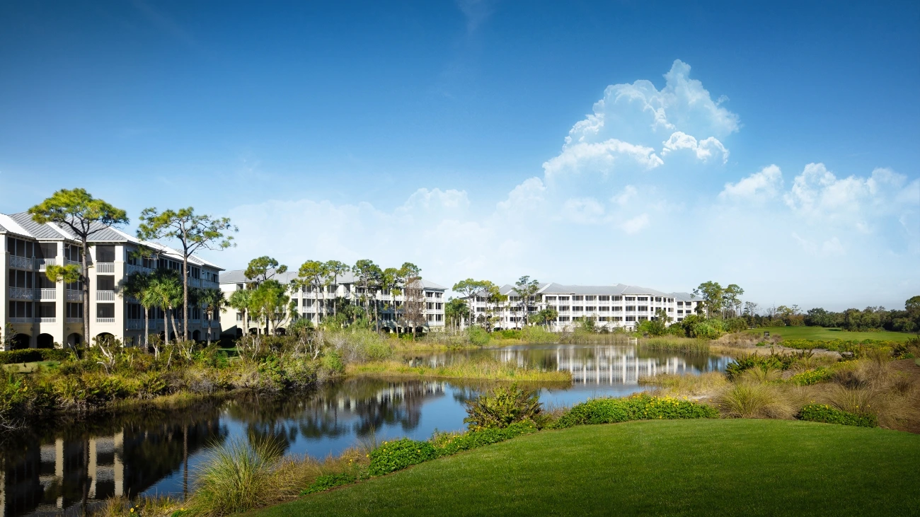View of green golf course, lake, and resort buildings