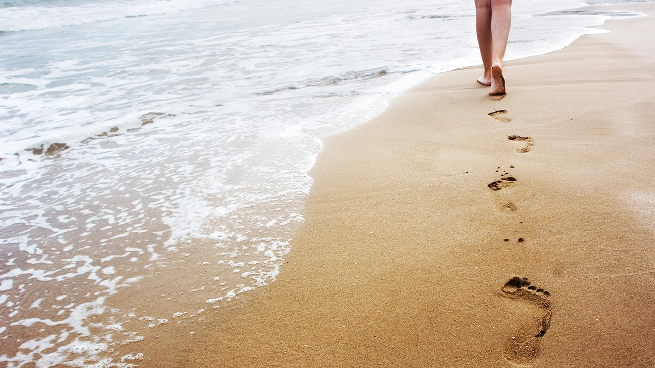 Woman walking barefoot along a beach