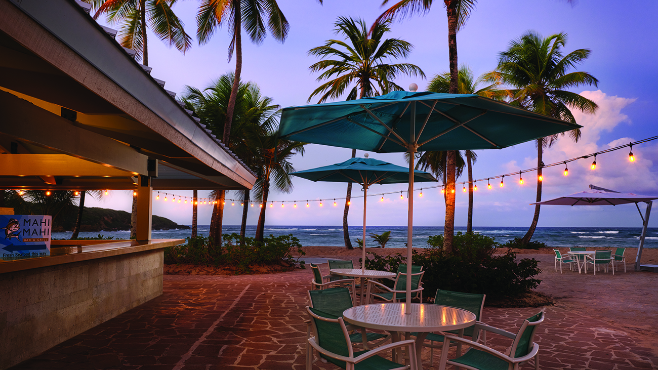 String of lights provide ambience to a pool bar next to the beach
