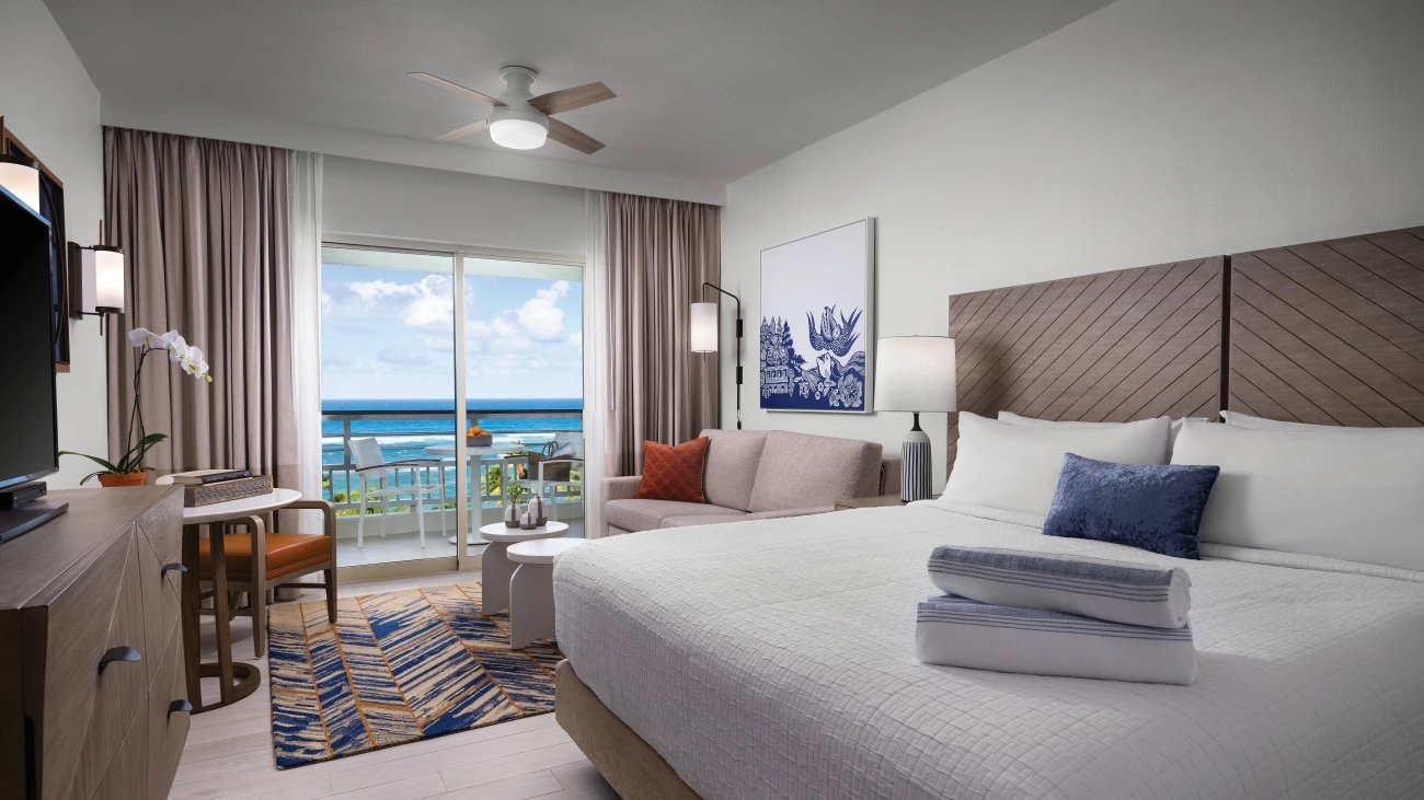Bedroom with table and chairs on a balcony overlooking the ocean