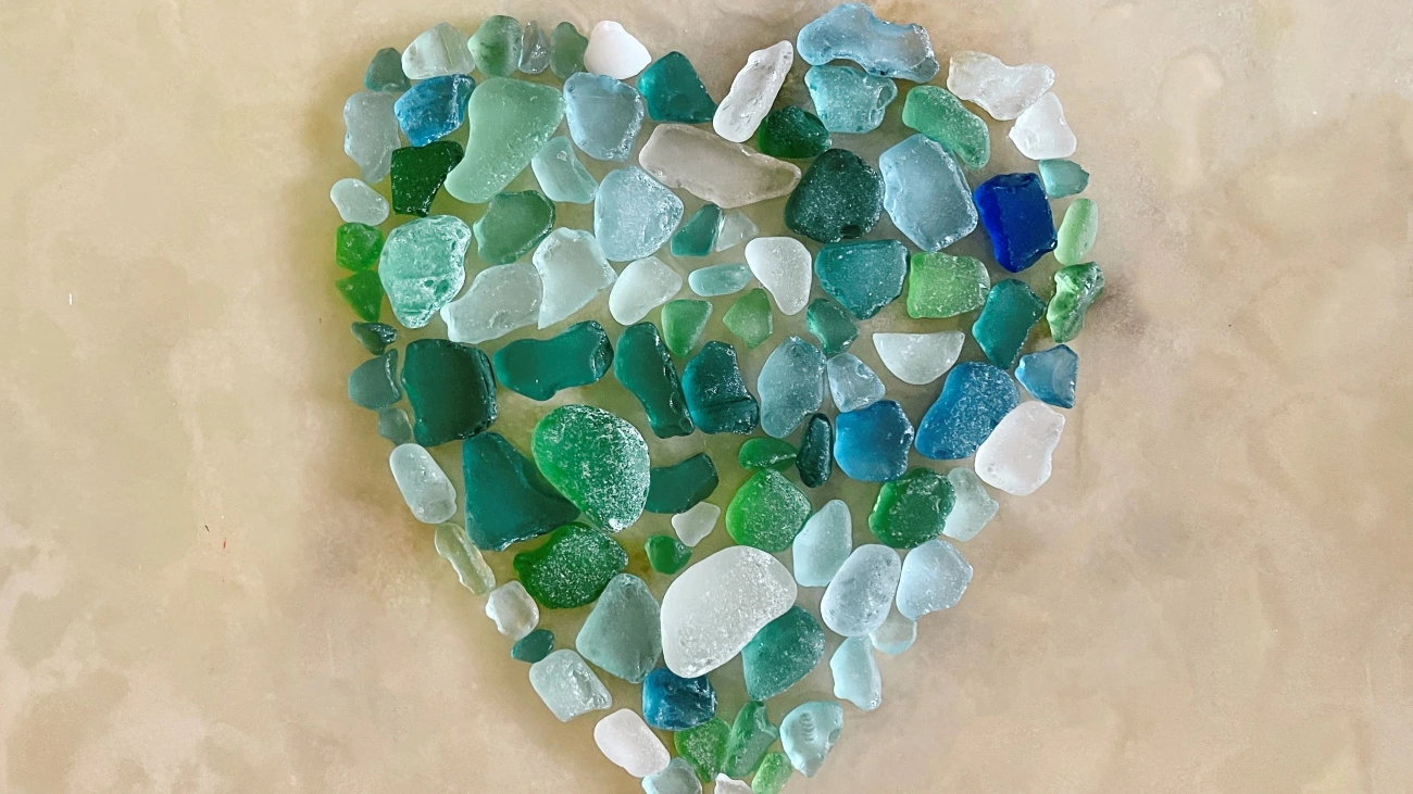 Vibrant pieces of green and aqua sea glass arranged in a heart shape