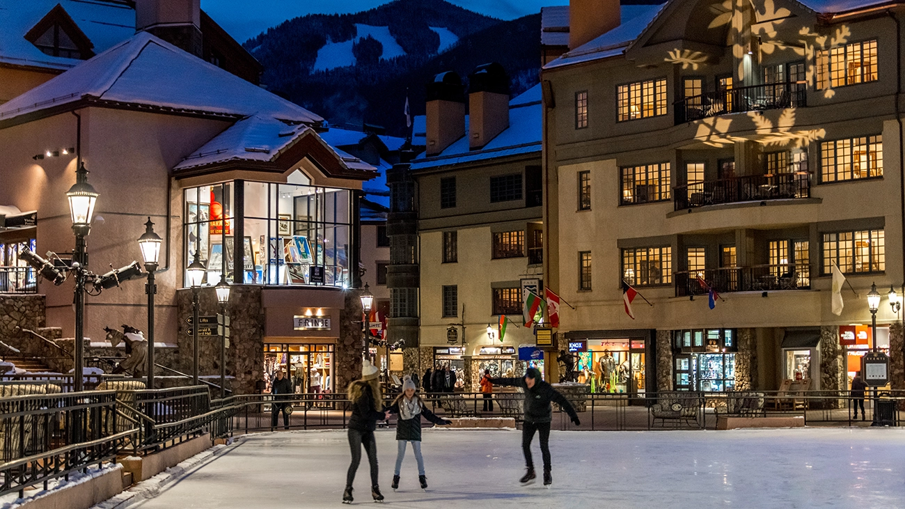 Three guests enjoy ice skating  as nighttime falls over the resort