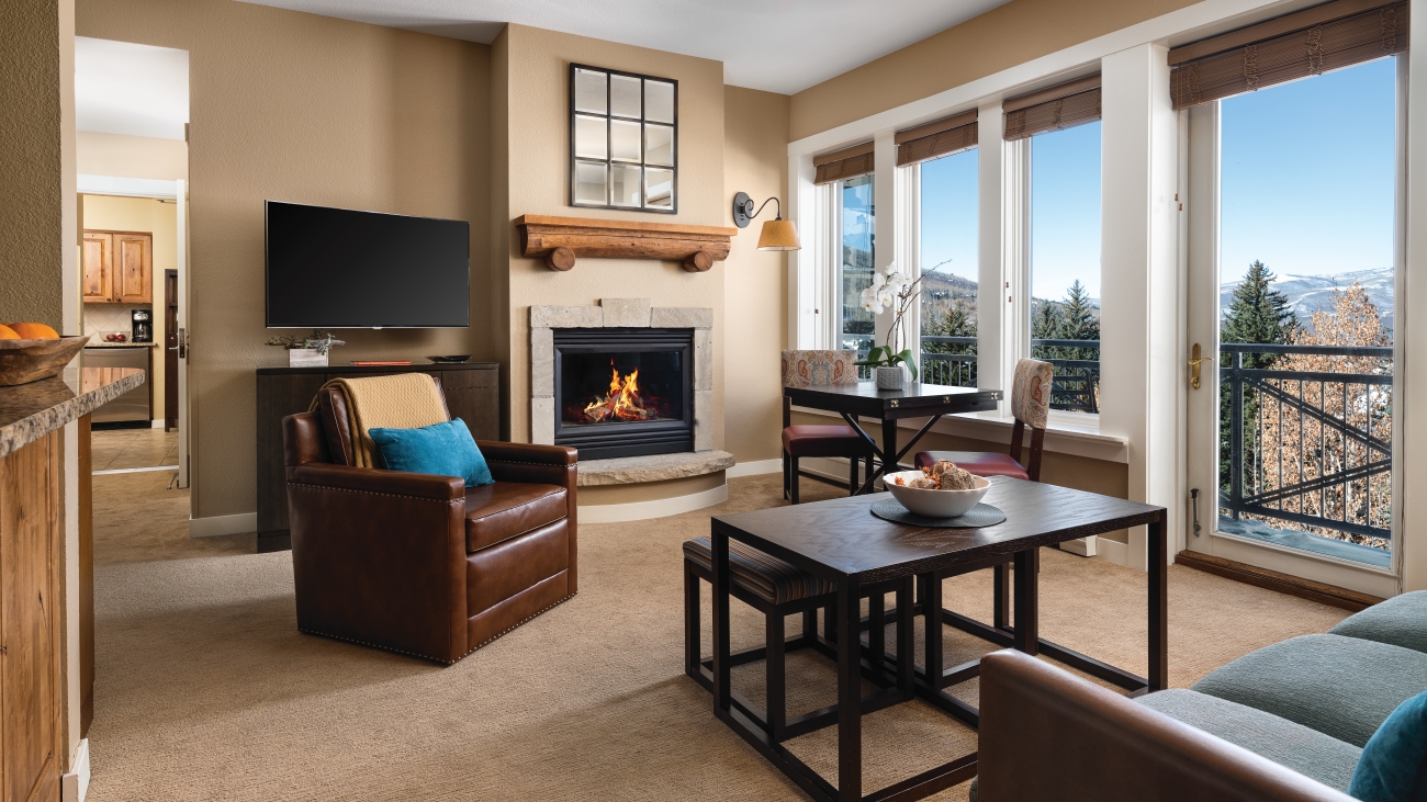 Interior view of mountain villa with brown leather armchair, sofa, HDTV, and working fireplace