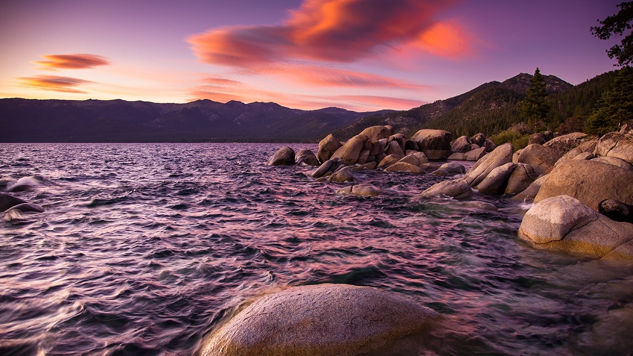 Shimmering lake water along a ruggedly beautiful rocky shore at sunset