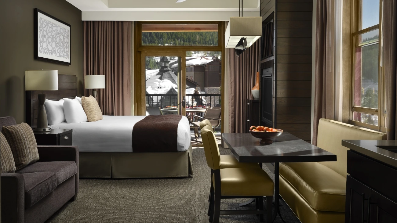 Interior view of resort bedroom with bed, banquette, loveseat, and decorative bowl of fruit