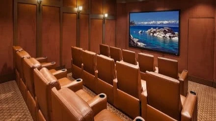 Private indoor movie theater with large screen and comfortable brown leather seating