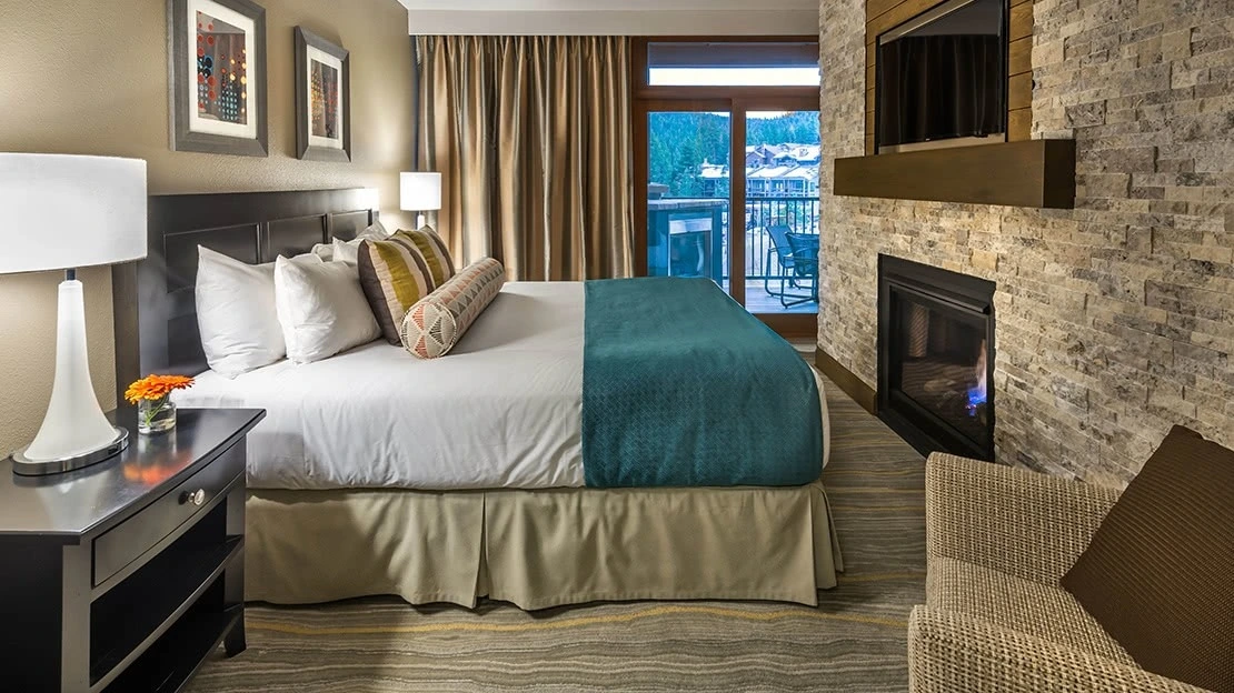 Interior view of villa bedroom with HDTV, working fireplace, and teal and tan accents