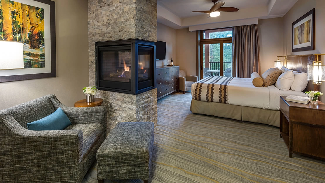 Cozy villa interior with armchair, bed, dresser, and working fireplace