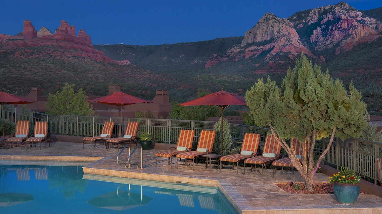 Red rocky mountains sit behind a resort pool deck