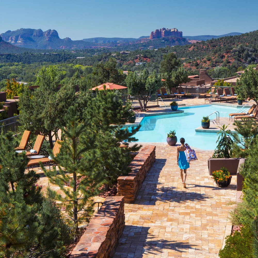 A guest walks across the tile to the Pinon Pointe pool with mountains in the background