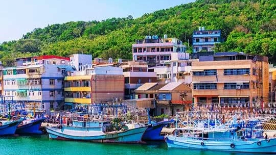 Boats at a dock on the water with colorful buildings