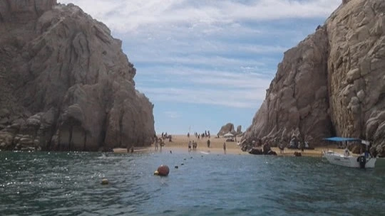 View of the beach from the water with rock formations and people