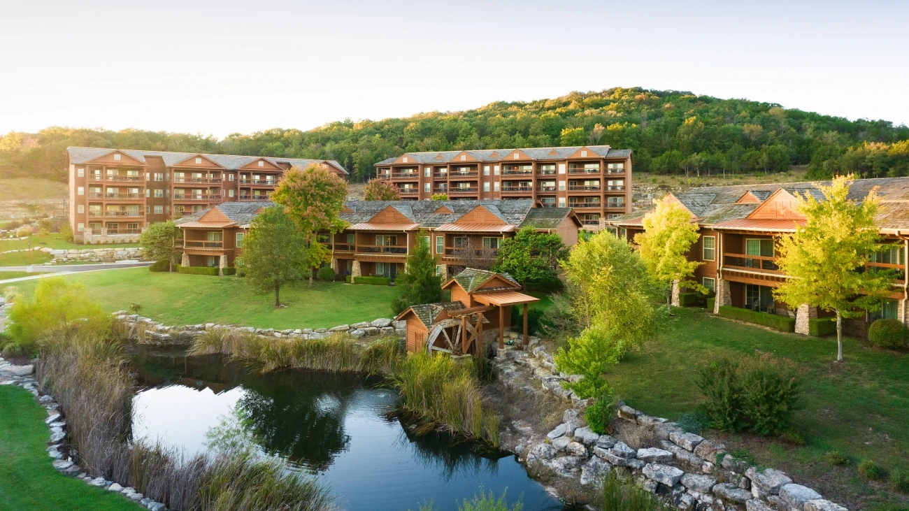 Rustic resort with a pond and forested hills in the distance