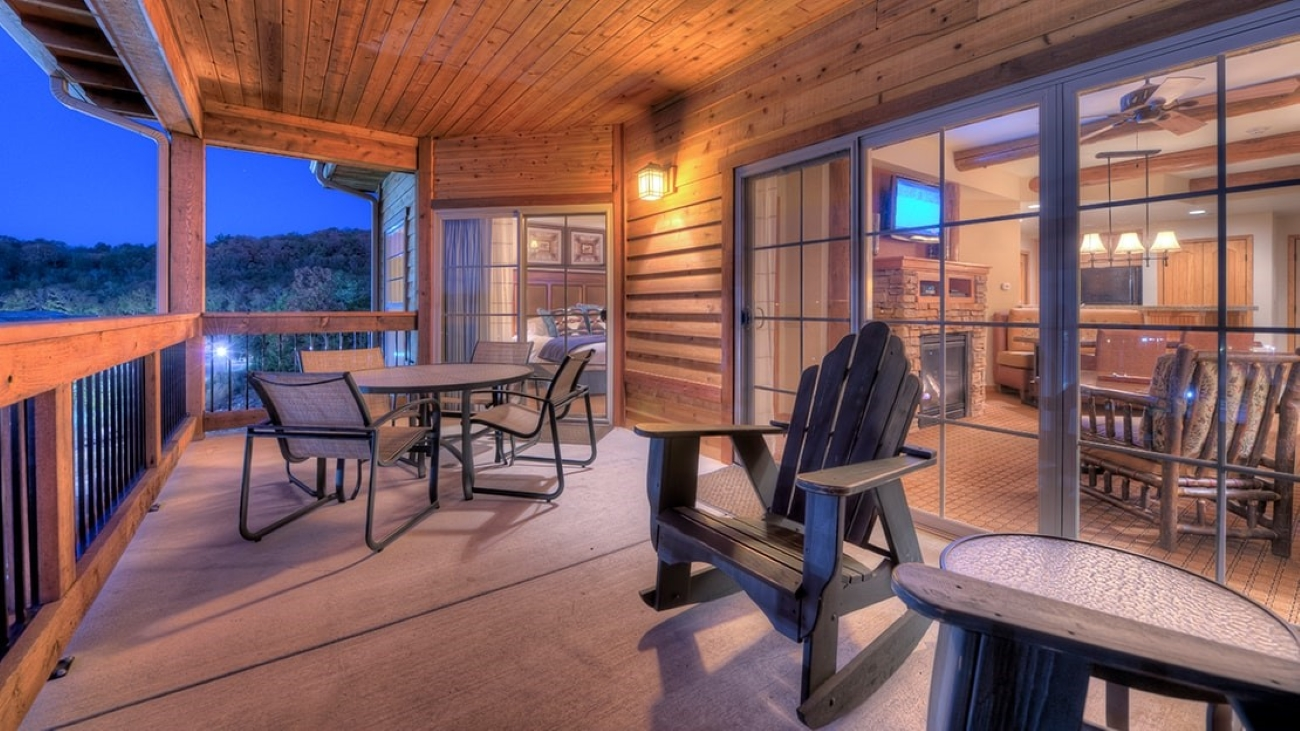A balcony outside a wooden-clad resort with chairs and tables