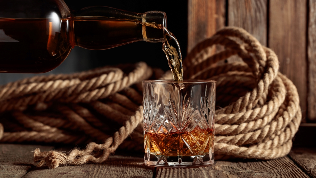 Pouring amber-colored whiskey into a rocks glass
