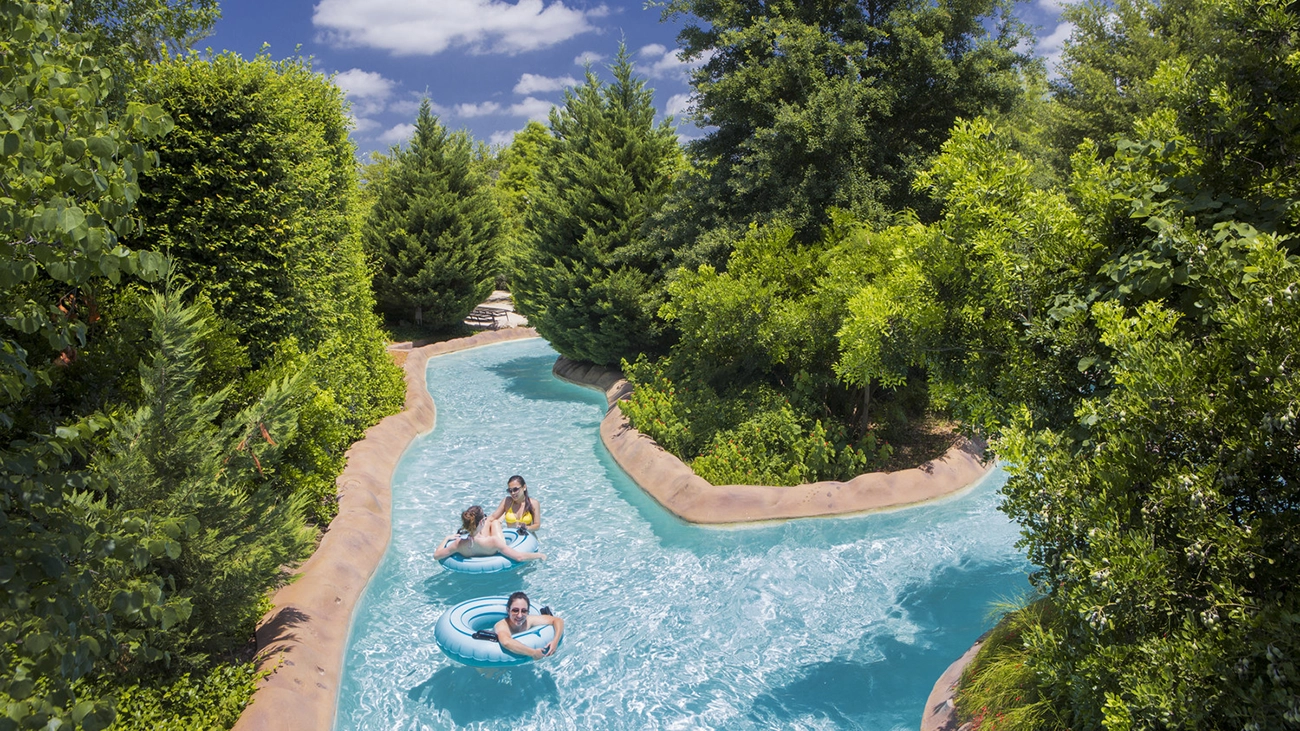 A few guests sit in innertubes and float down a tree-lined lazy river