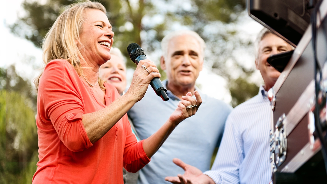 A group of people singing into a microphone and smiling